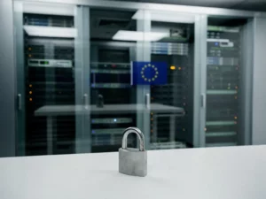 Europese serverruimte met Dutch-designed hardware achter glazen paneel, EU-vlag reflectie en hangslot op wit bureau op de voorgrond.